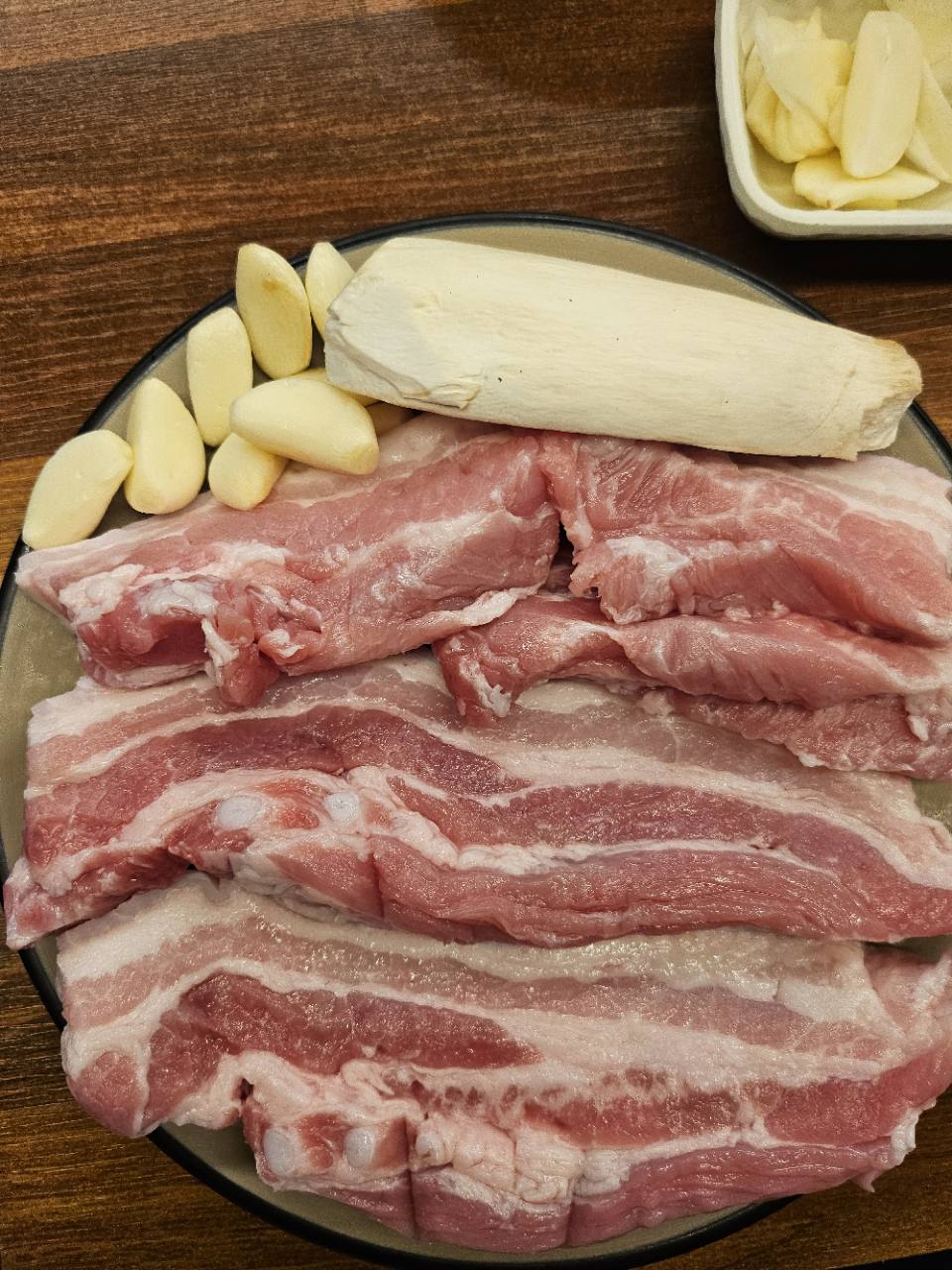 청수식당오산시청점에서 주문해 촬영한 삼겹살과 새송이버섯, 마늘 접시