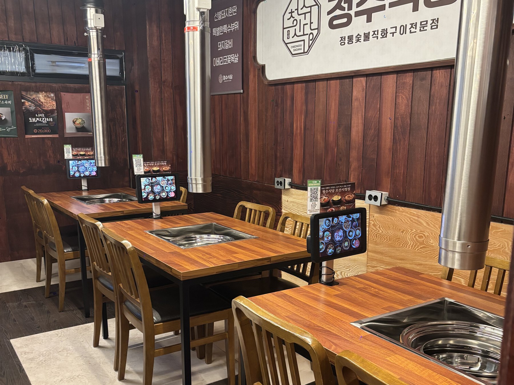 청수식당오산시청점의 벽면 벤치와 의자를 함께 배치한 여러 테이블